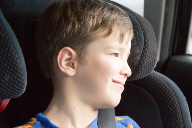 niño sonriendo mirando a través de la ventana del coche